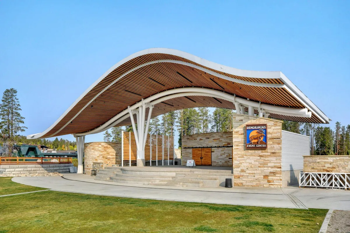 An open, curved-roof stage with stone walls hosts outdoor performances and community gatherings. The space is ready for concerts and events, embodying the spirit of Hideaway Park across the street from the property.