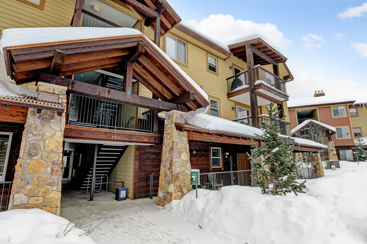 A welcoming exterior view of the property featuring wooden beams, a stone façade, balconies, and snow-covered ground. The scene emphasizes both the allure of winter landscapes and the comforts awaiting guests after a day of exploring.